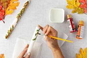 Painting leaves on candle.