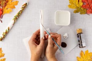 Painting branches on candle.