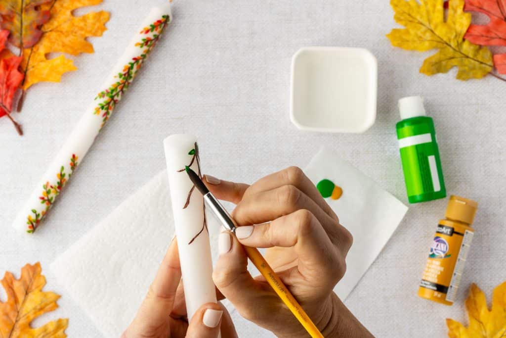 Painting leaves on candle.