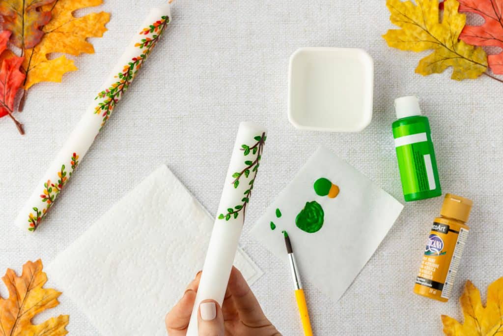 Painting leaves on candle.