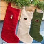 Three embroidered stockings hanging on a mantle.