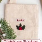 A beige stocking with holly embroidered and the name 'Ruby' embroidered on it.