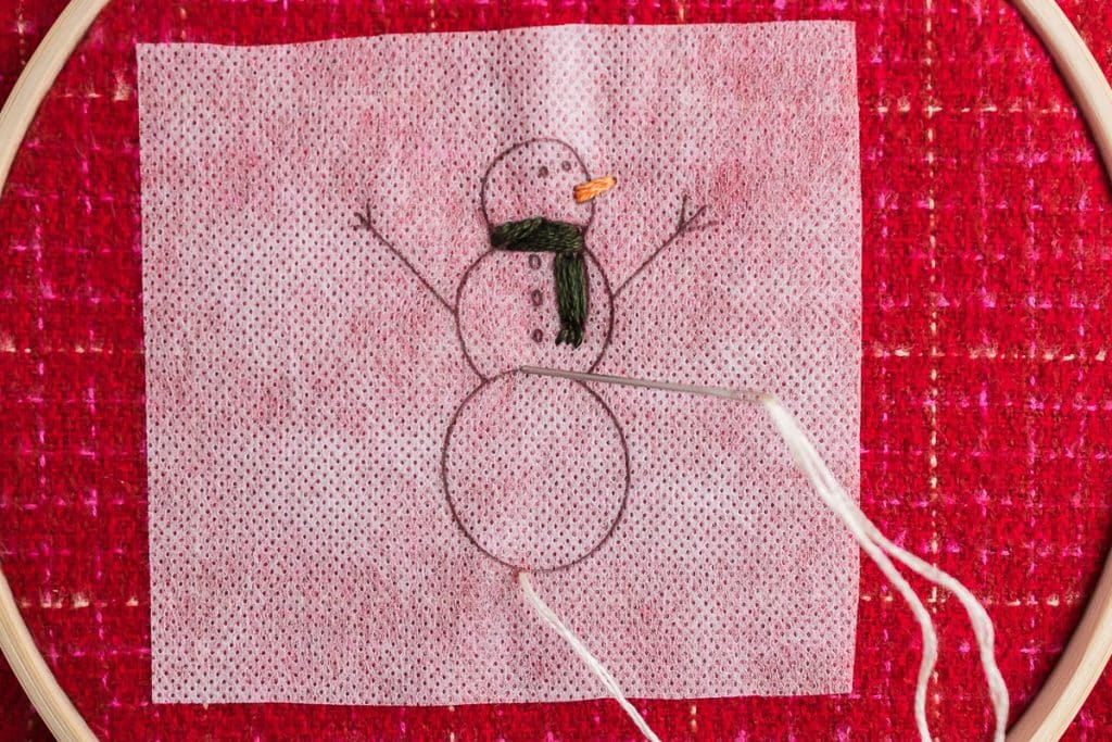 Sewing nose on snowman.