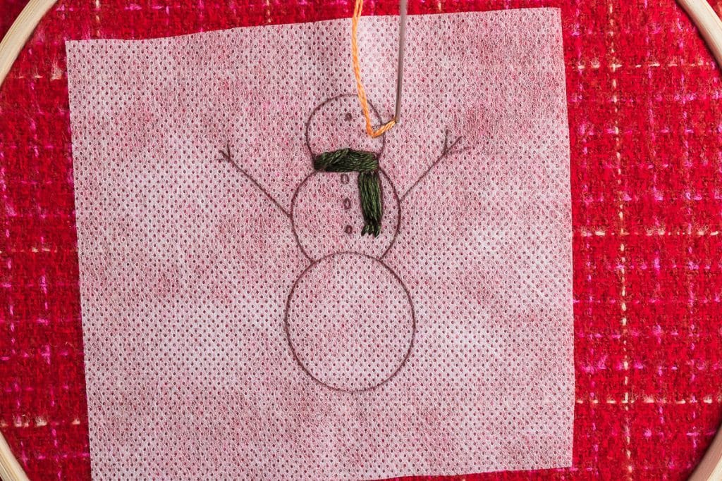 Sewing nose on snowman.