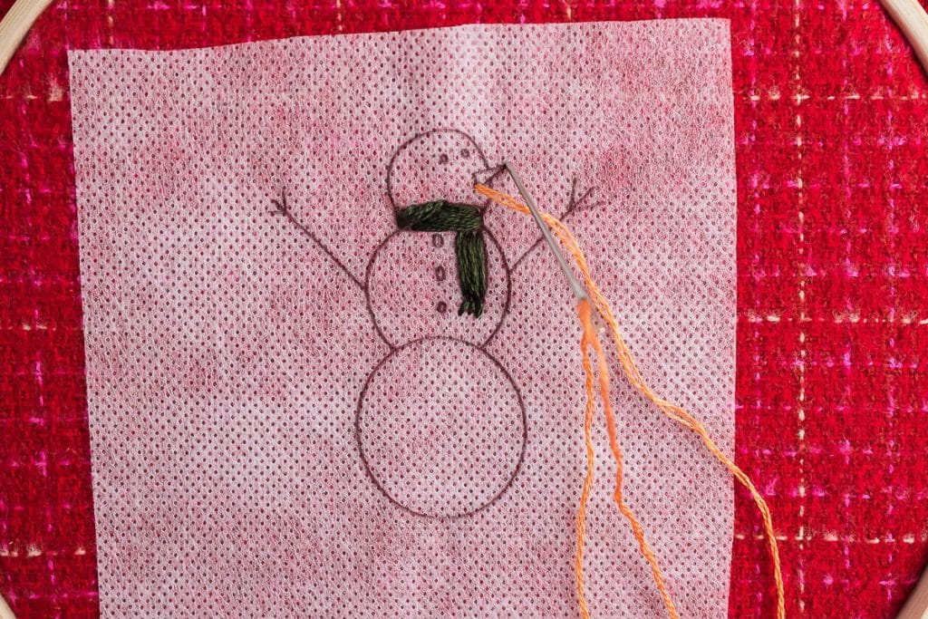 Sewing nose on snowman.