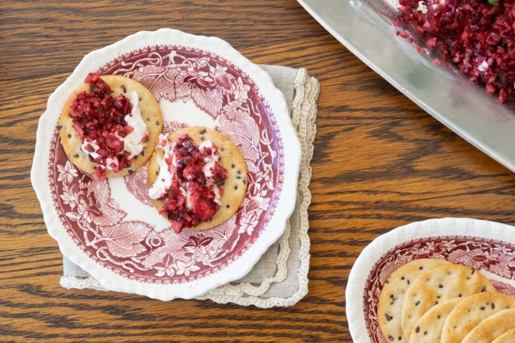 crackers with cheese spread on red and white plate.