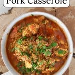 Slow cooker pork casserole in a white bowl on a slab of wood.