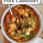 Slow cooker pork cassoulet in a white bowl on a slab of wood.