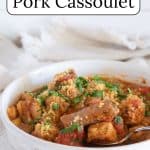 Slow cooker pork cassoulet in a white bowl on a slab of wood.