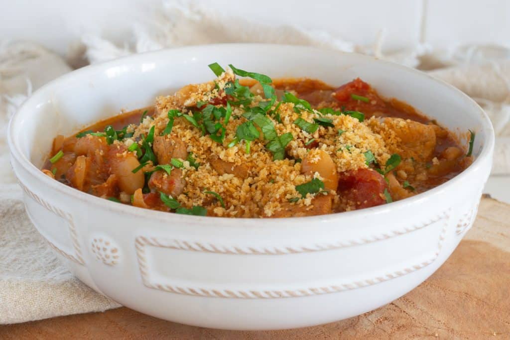 Slow cooker pork casserole in a white bowl on a slab of wood.