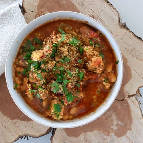 Slow cooker pork casserole in a white bowl on a slab of wood.