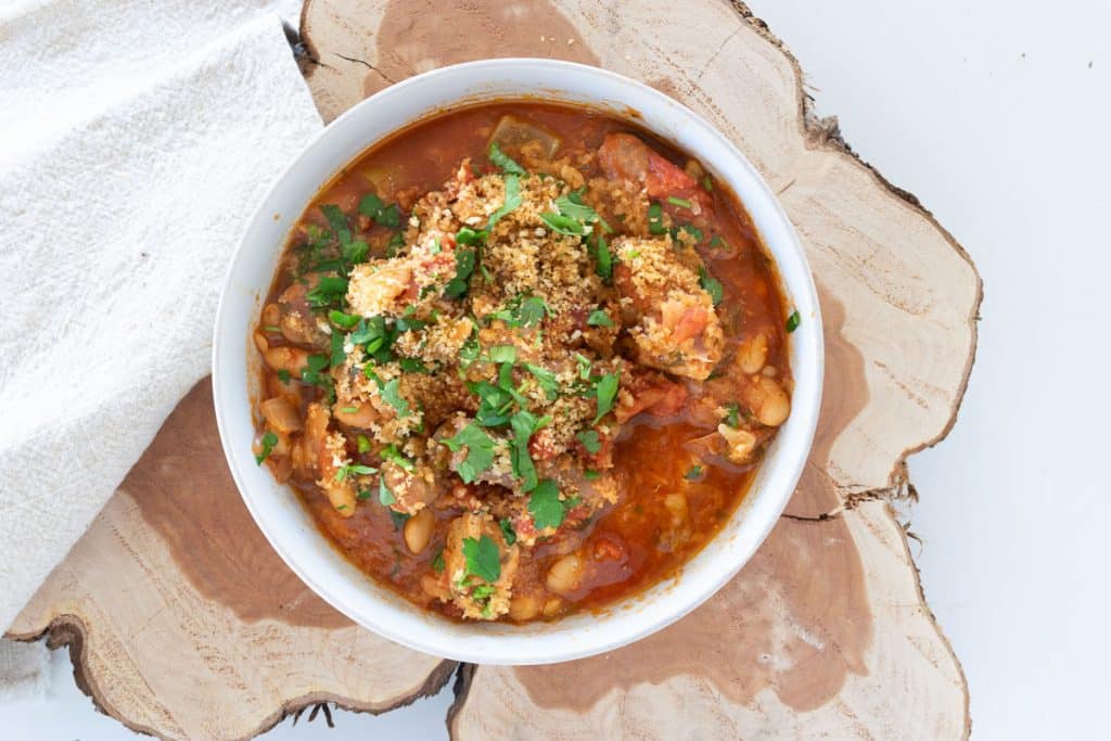 Slow cooker pork casserole in a white bowl on a slab of wood.