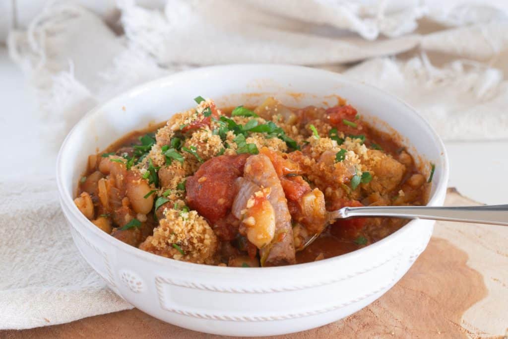 Slow cooker pork casserole in a white bowl on a slab of wood.