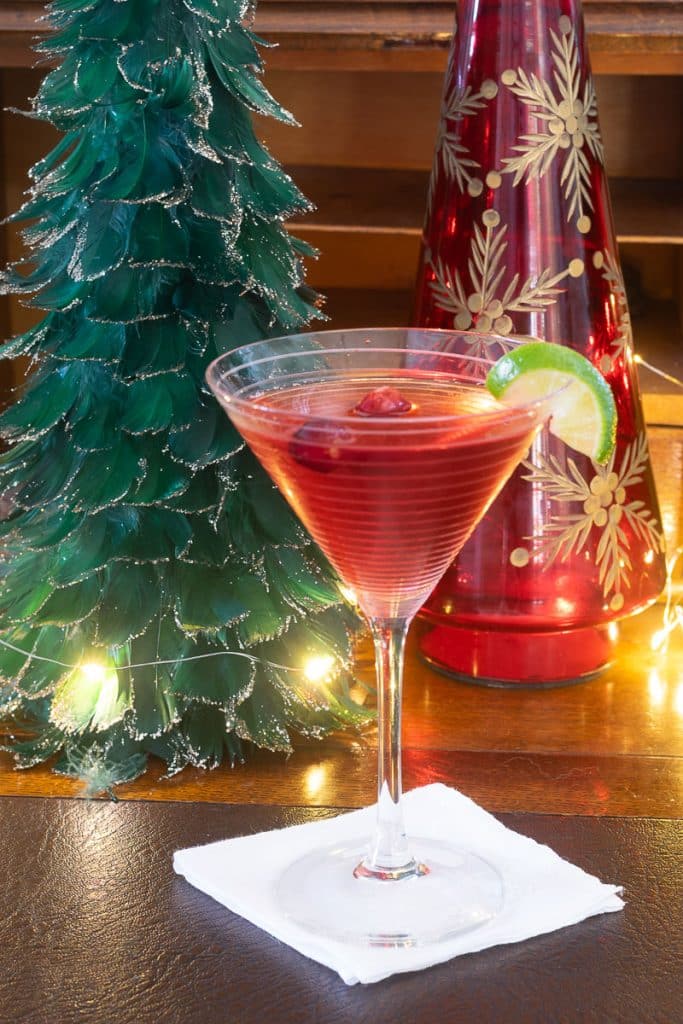 Holiday Cosmo in front of feather Christmas trees.