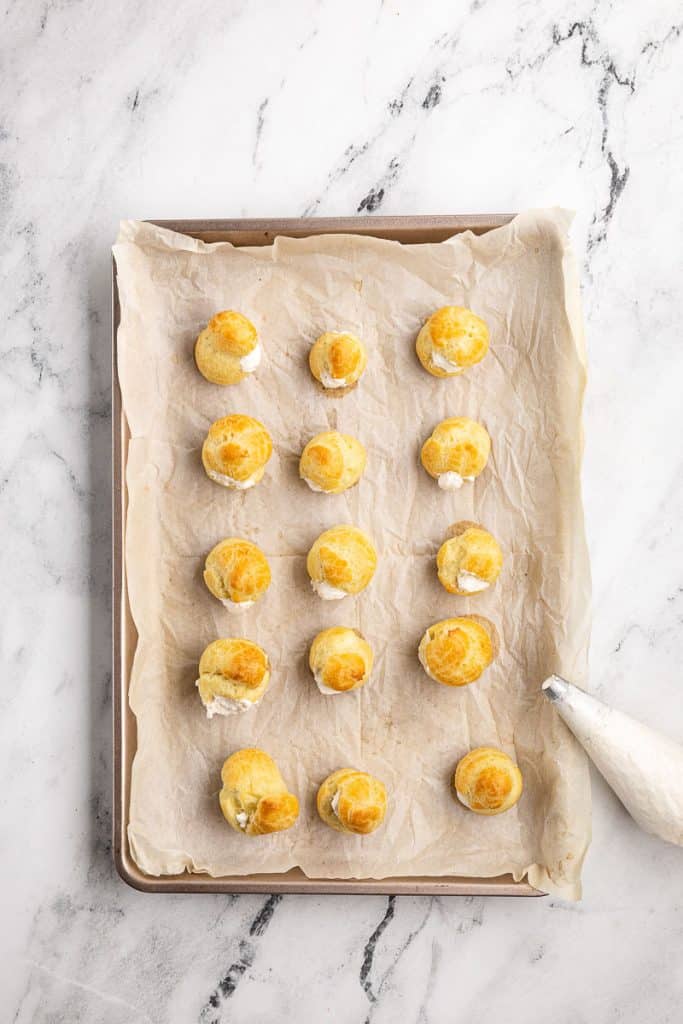 Piping cream into profiteroles.