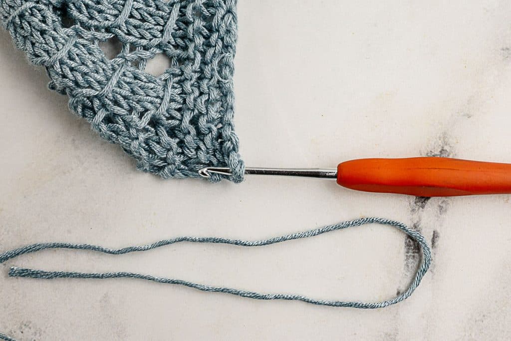 Use you crochet hook to pull the fringe yarn through the end of the scarf.