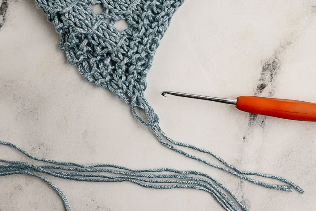 Use you crochet hook to pull the fringe yarn through the end of the scarf.