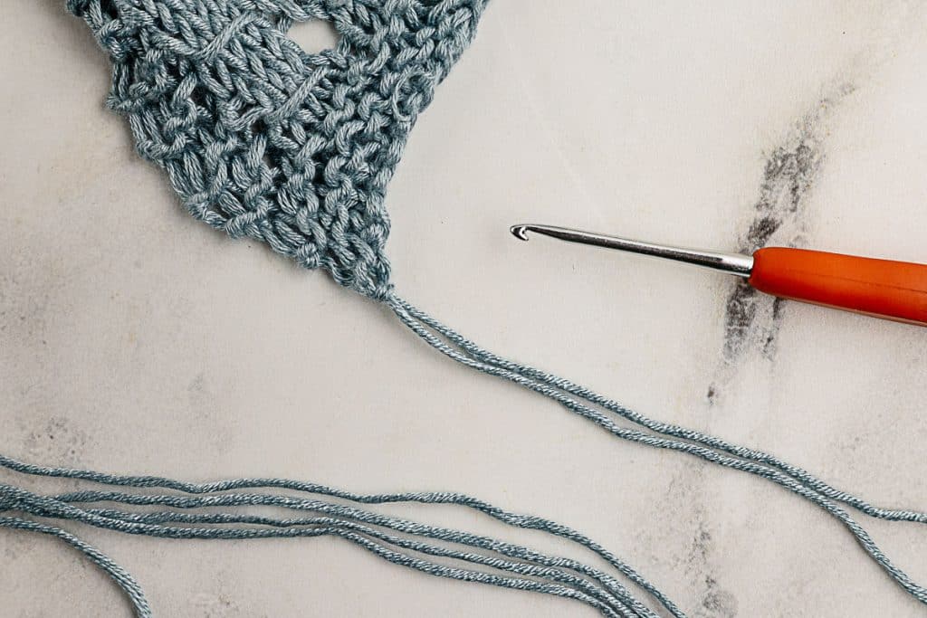 Use you crochet hook to pull the fringe yarn through the end of the scarf.