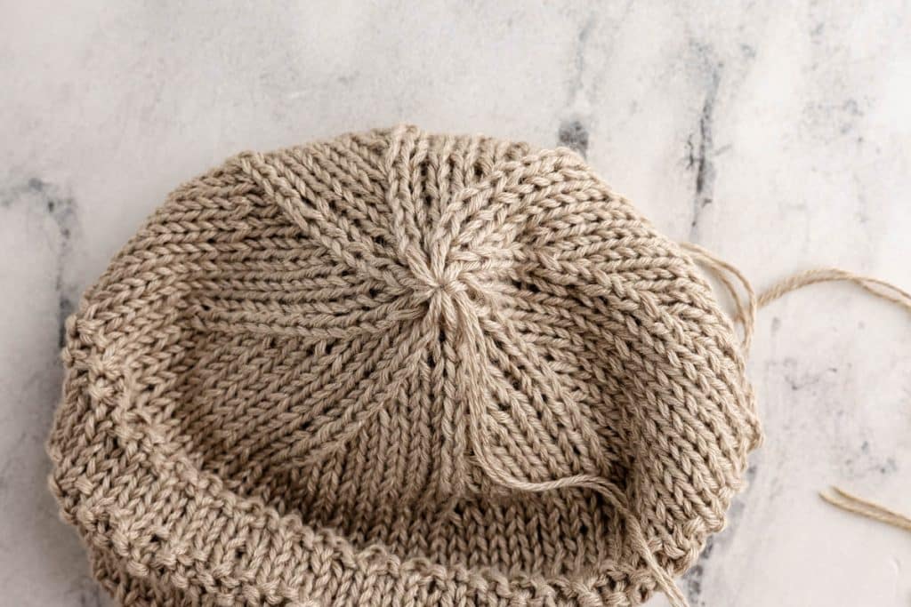 Last stitches before closing the knit baby hat.