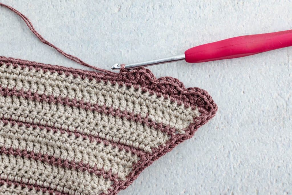 Crocheting scallop border on scarf.