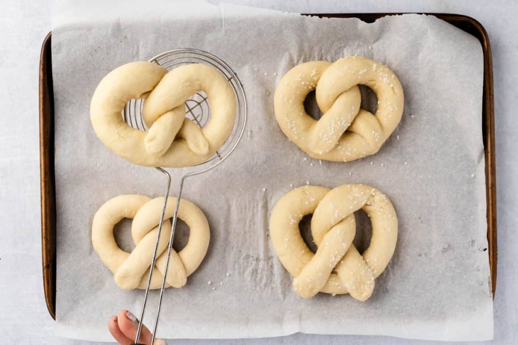 Picking up pretzel to boil.